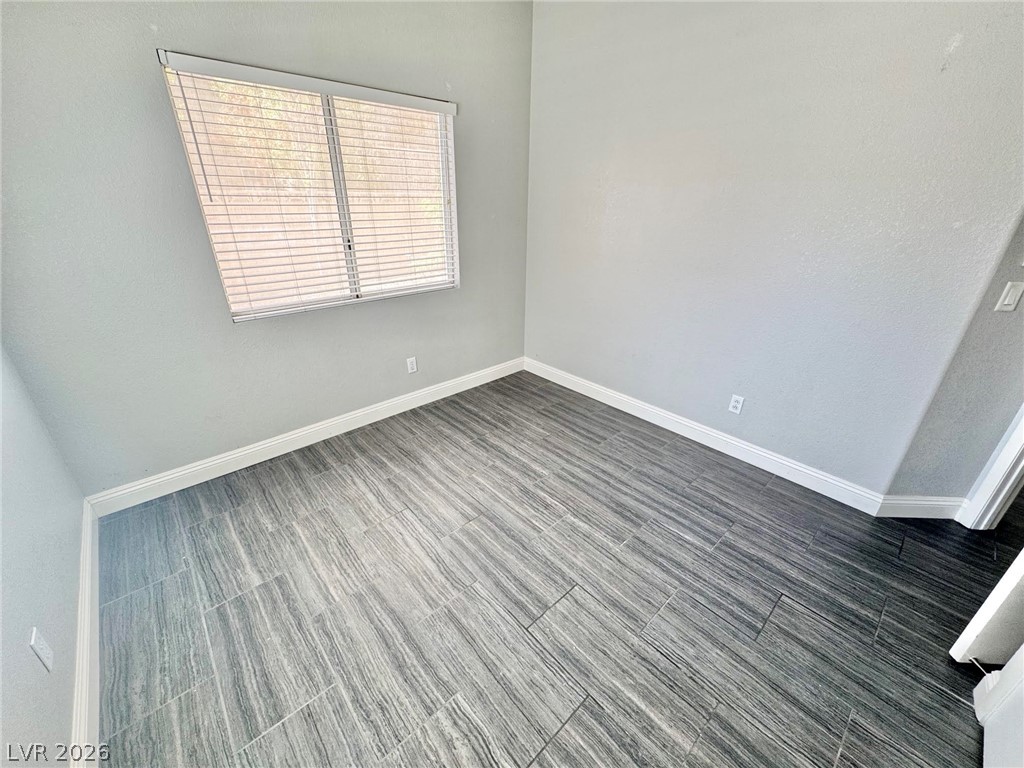 5304 Runningbrook Road Las Vegas, NV 89120 - Photo 14 of 22 Textured flooring and tall baseboards anchor this versatile empty room illuminated by natural light.