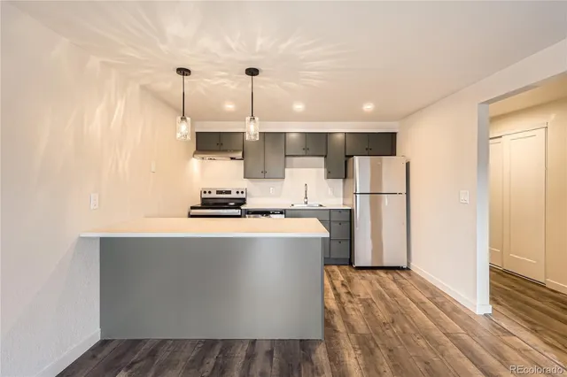 a kitchen with stainless steel appliances granite countertop a refrigerator a sink dishwasher a stove and a wooden floors