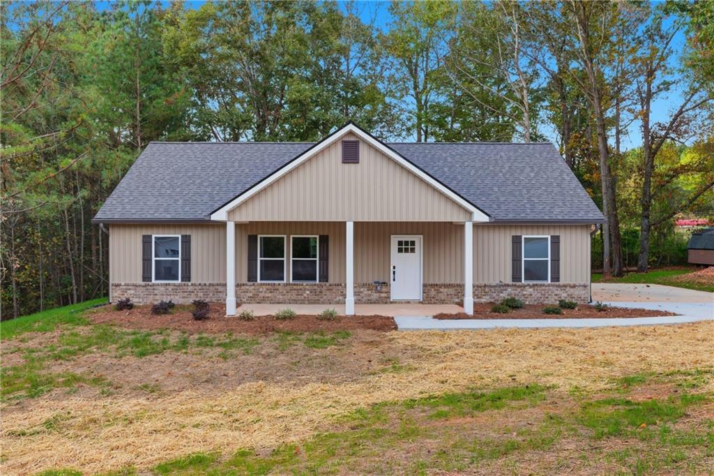 a front view of a house with yard and trees in the background