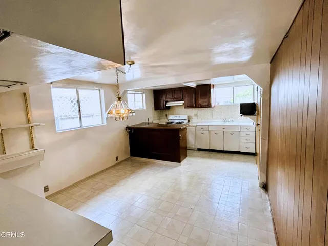 a living room with stainless steel appliances kitchen island granite countertop a refrigerator and a stove top oven