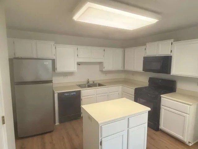 a kitchen with a sink a stove a refrigerator and white cabinets