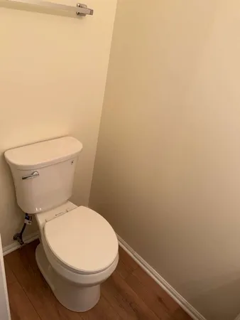 a white toilet sitting next to a white wall