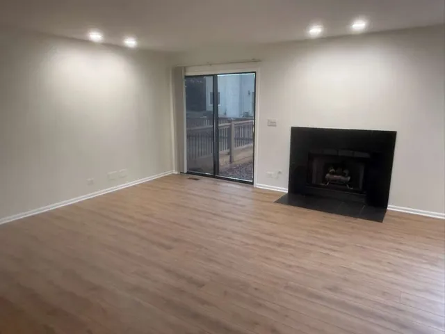 a view of an empty room with wooden floor and a fireplace
