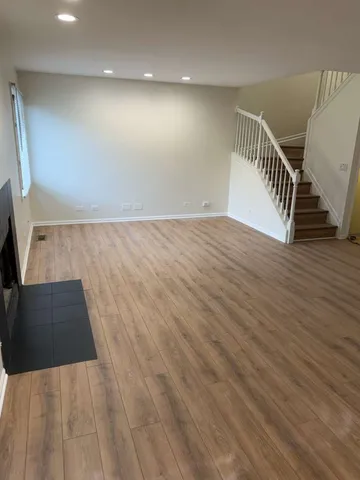 a view of a livingroom with wooden floor and staircase