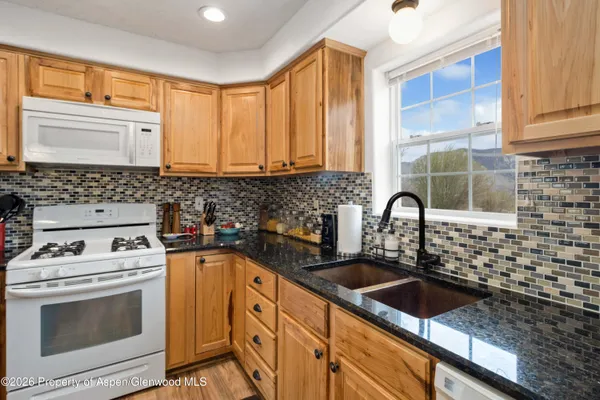 a kitchen with granite countertop a sink a stove and cabinets