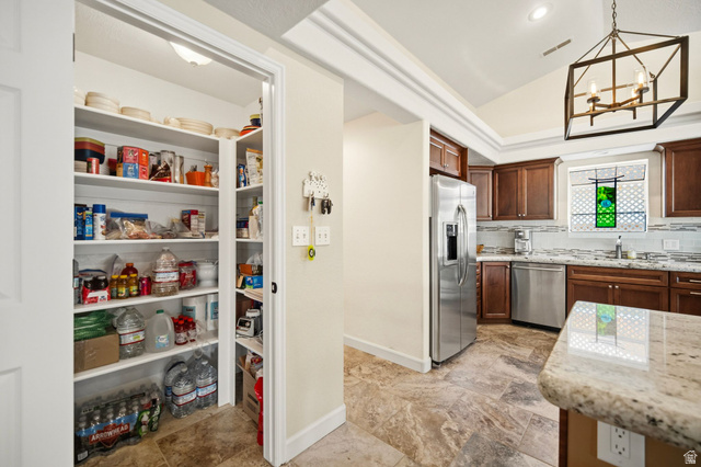 1985 West Rivers Edge Lane St. George, UT 84770 - Photo 20 of 42 Kitchen featuring lofted ceiling, decorative backsplash, stainless steel appliances, light stone countertops, and hanging lights