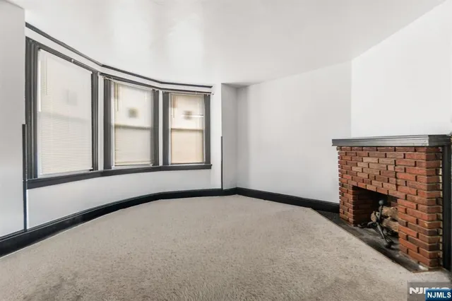 a view of an empty room with a fireplace and a window