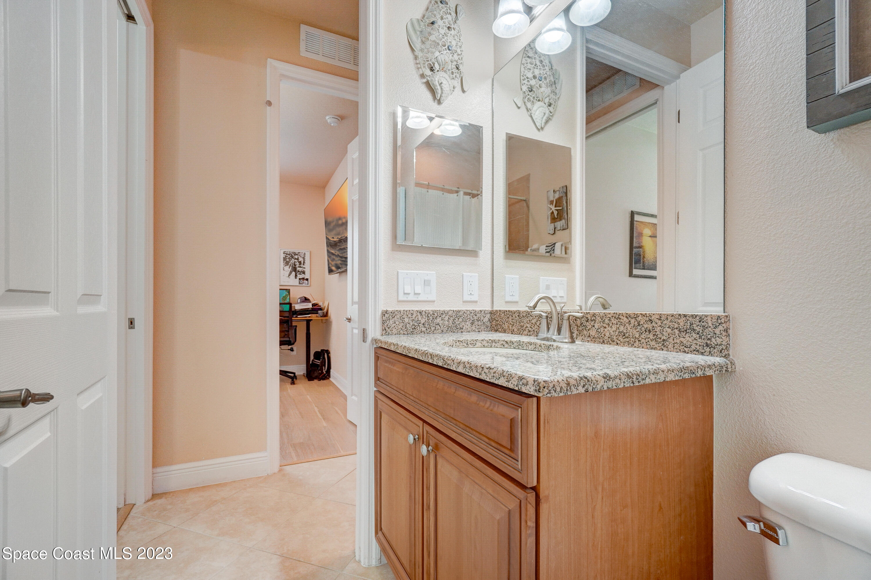 1568 Outrigger Circle Rockledge, FL 32955 - Photo 20 of 44 a bathroom with a granite countertop sink a toilet and a mirror
