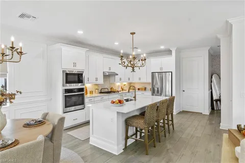 a kitchen with stainless steel appliances a table chairs and refrigerator
