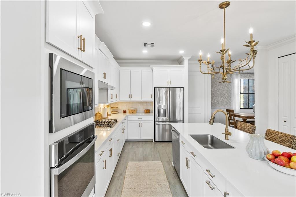 20507 Napa Loop Estero, FL 33928 - Photo 13 of 49 a kitchen with a refrigerator a stove a sink dishwasher a oven with a dining table and chairs