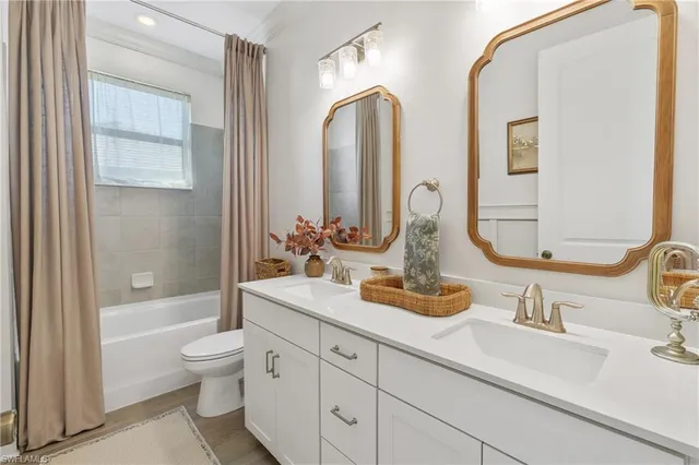 a bathroom with double vanity sinks a toilet and a large mirror