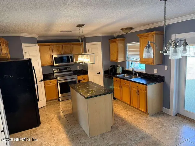 a kitchen with stainless steel appliances a stove a refrigerator a sink a stove top oven and a refrigerator