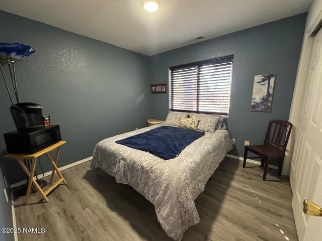 a bedroom with a bed a chair and a dresser next to a window