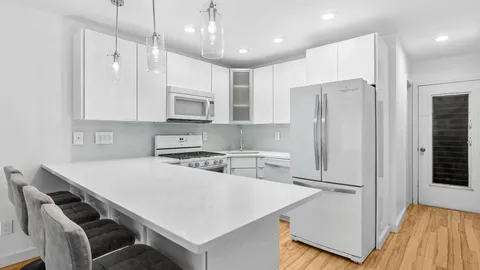 a kitchen with stainless steel appliances granite countertop a refrigerator a sink dishwasher a stove and white cabinets with wooden floor