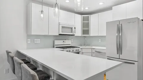 a kitchen with stainless steel appliances a refrigerator a sink a stove a microwave and white cabinets