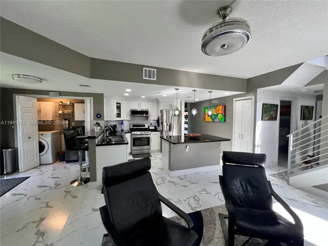 a living room with furniture a dining table chairs and a chandelier