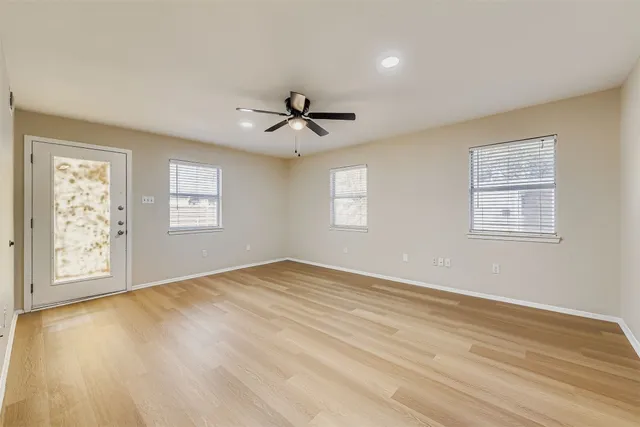 a view of an empty room with a window and wooden floor