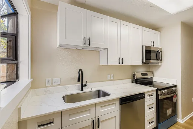 a kitchen with white cabinets a sink and appliances