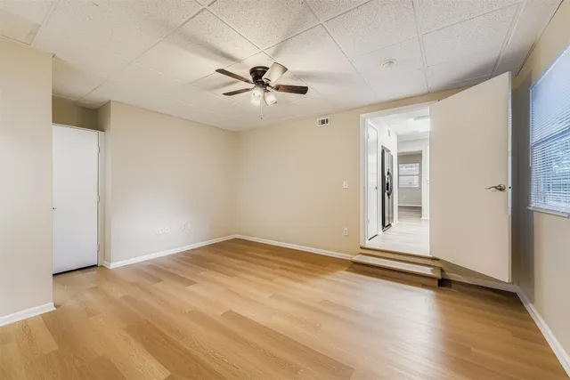 a view of an empty room with wooden floor and a window