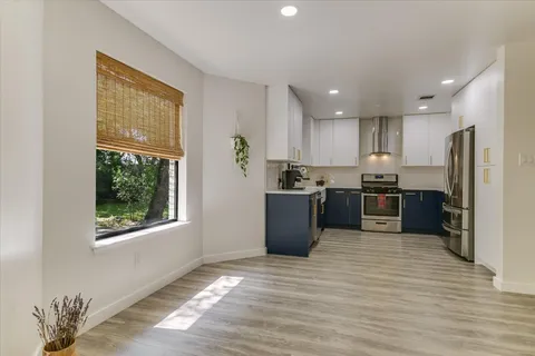 a kitchen with stainless steel appliances granite countertop a refrigerator a sink a stove and a refrigerator