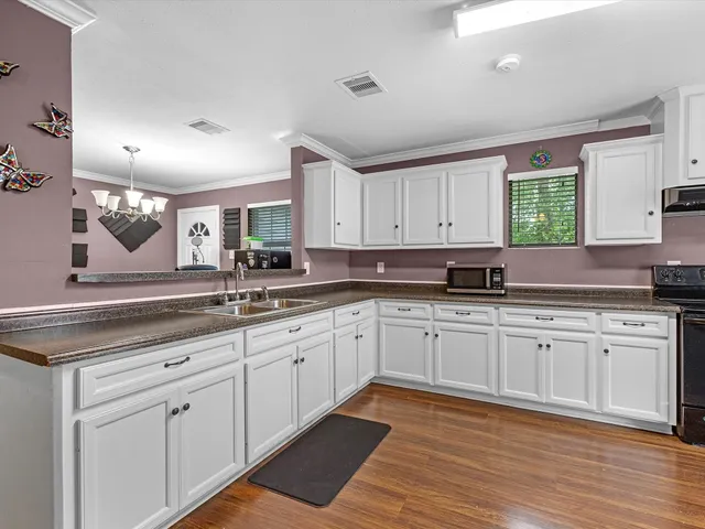 a kitchen with granite countertop white cabinets white appliances with a sink and dishwasher next to a window