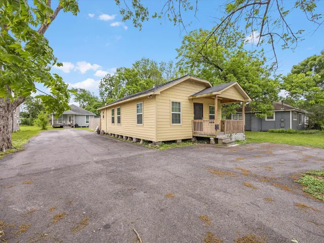 a view of a house with a yard and large tree