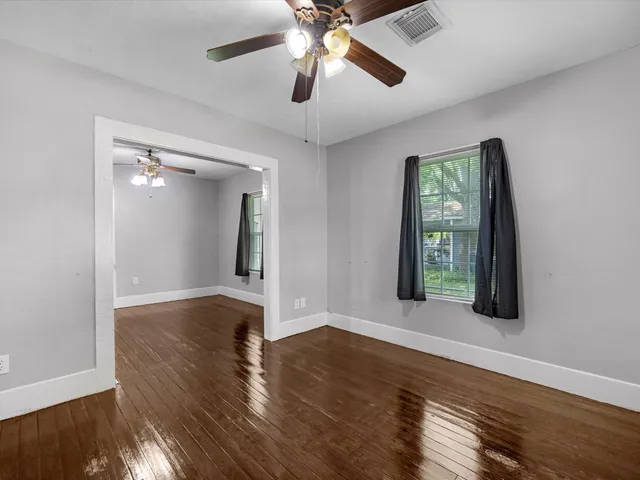 a view of an empty room with wooden floor and a window
