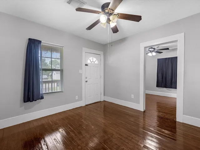 a view of an empty room with wooden floor and a window