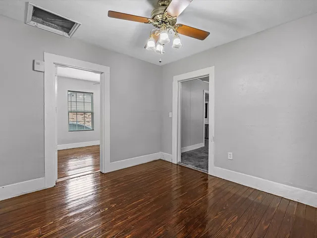 a view of an empty room with window wooden floor and a ceiling fan