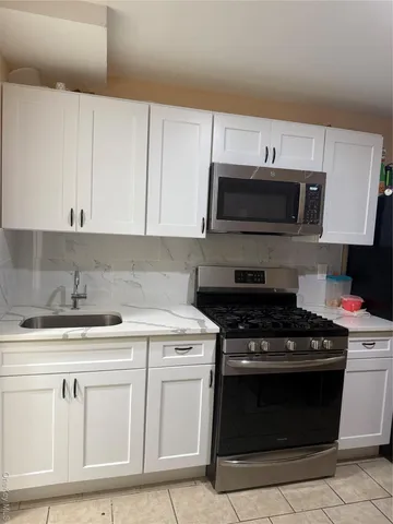 a kitchen with white cabinets and stainless steel appliances