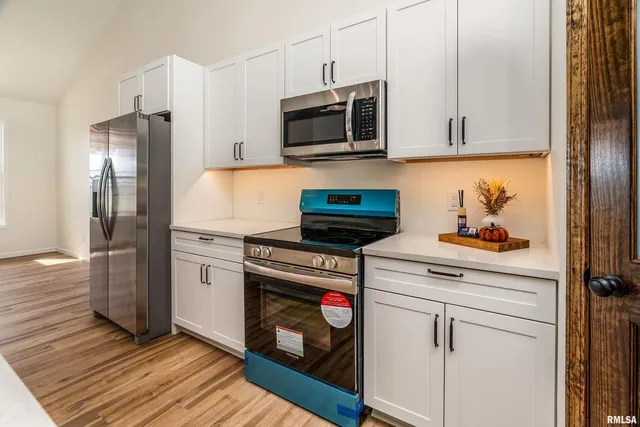 a kitchen with stainless steel appliances white cabinets and wooden floor