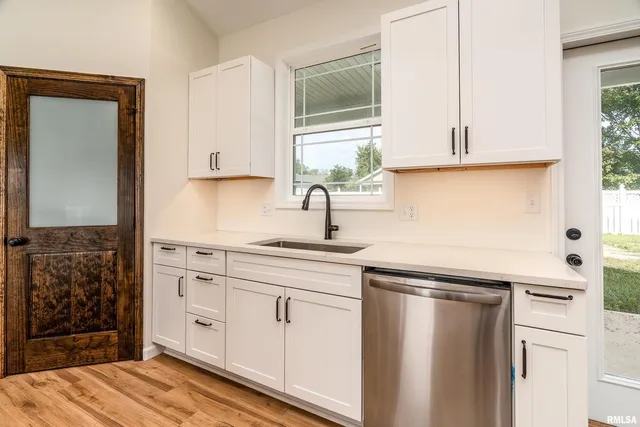a kitchen with white cabinets and sink
