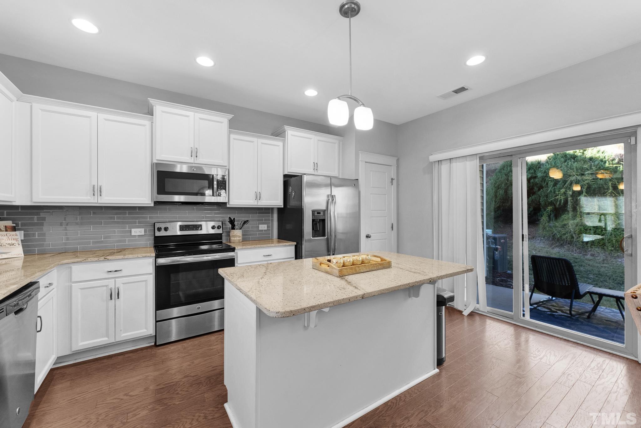 7810 Allscott Way Raleigh, NC 27612 - Photo 15 of 29 a kitchen with stainless steel appliances kitchen island a table chairs refrigerator and microwave