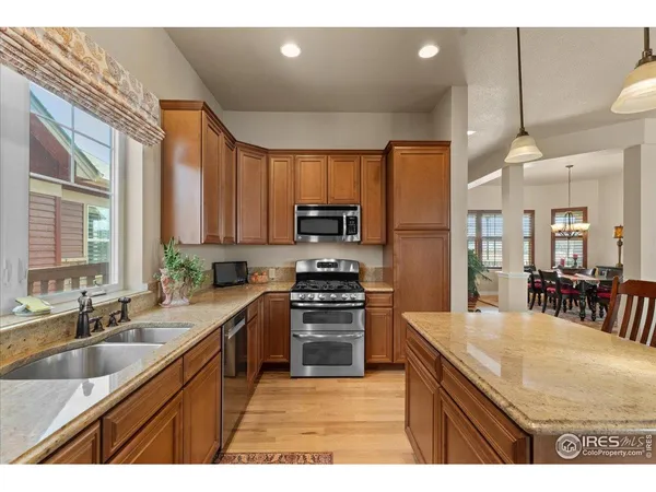 a kitchen with stainless steel appliances granite countertop table chairs sink refrigerator and microwave