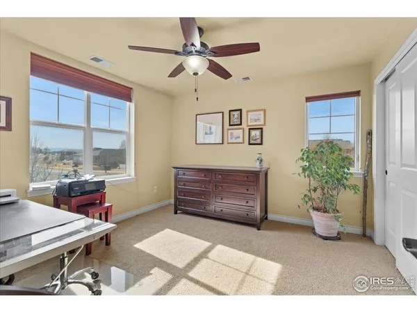 a view of an empty room with window and ceiling fan