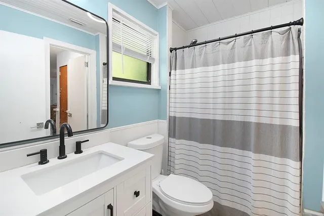 a bathroom with a sink a toilet and shower curtain