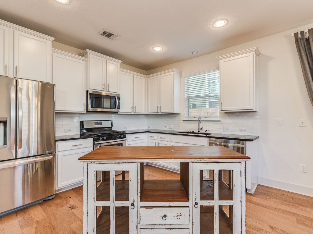 2208 Capulet Street Austin, TX 78741 - Photo 7 of 23 a kitchen with granite countertop a refrigerator stove and microwave