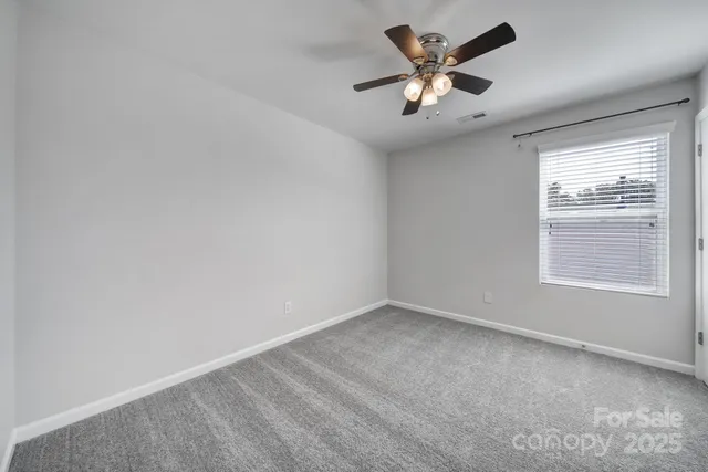 an empty room with window and ceiling fan