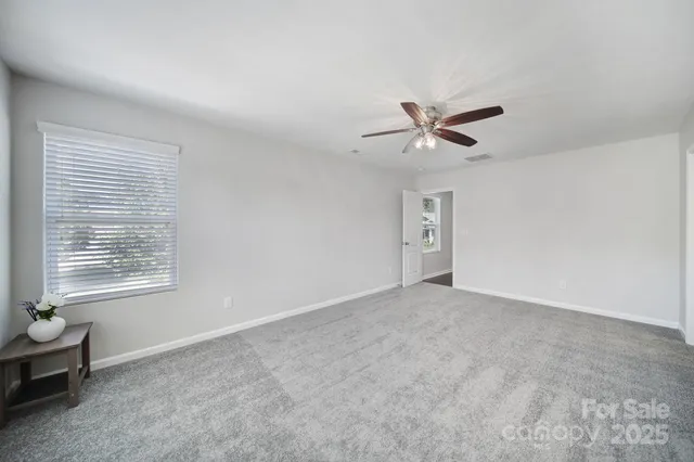 an empty room with fan and windows