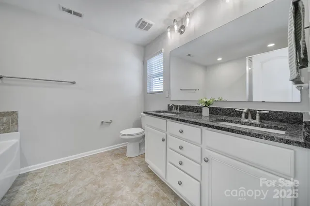 a bathroom with a granite countertop sink mirror and toilet