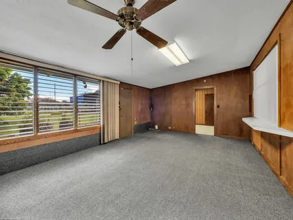 an empty room with windows and fan