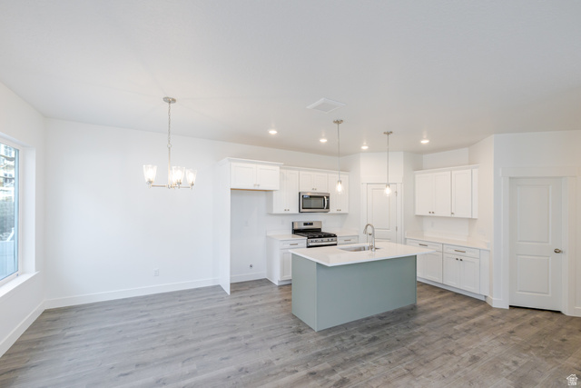 4769 Olive Avenue, Unit 411 Mapleton, UT 84664 - Photo 3 of 19 Two tone kitchen featuring an island with sink, stainless steel appliances, light wood-type flooring, dual tone cabinetry, and hanging lights