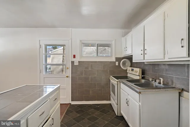 a kitchen with granite countertop a sink a stove and cabinets