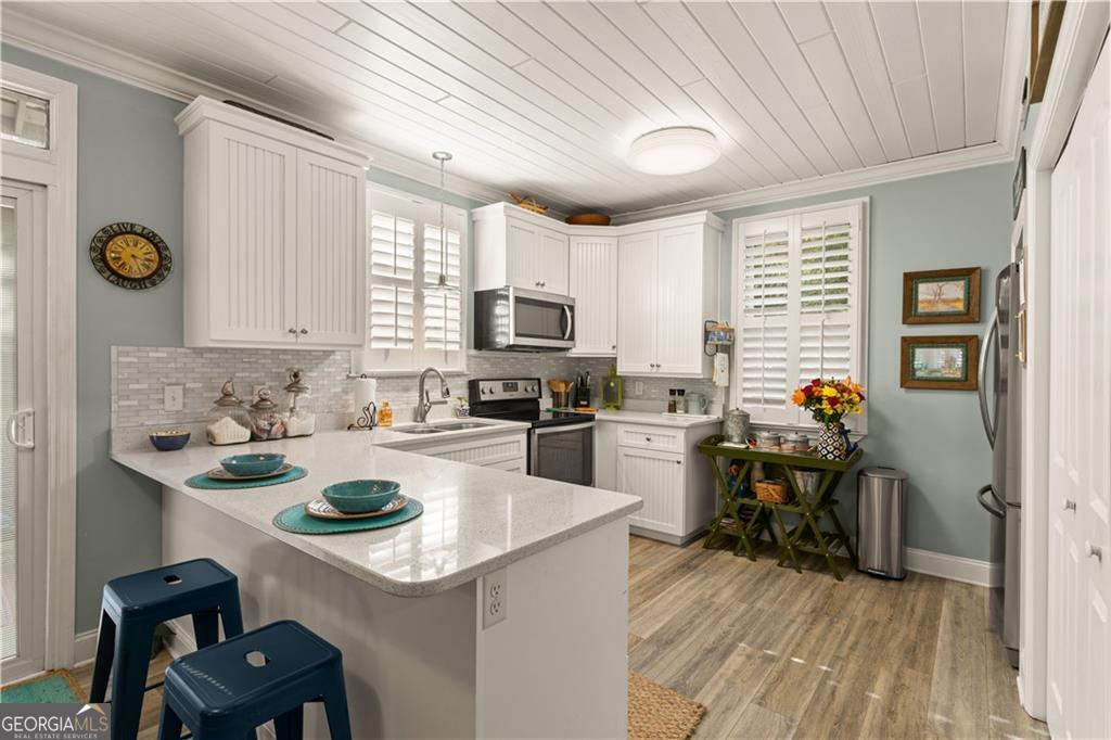 1035 Beach View Drive, Unit 201 St. Simons, GA 31522 - Photo 11 of 18 a kitchen with a sink a stove and chairs