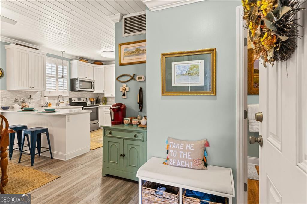 1035 Beach View Drive, Unit 201 St. Simons, GA 31522 - Photo 7 of 18 a kitchen with stainless steel appliances a stove a sink and white cabinets with wooden floor