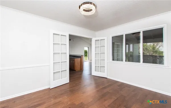 an empty room with wooden floor cabinet and windows