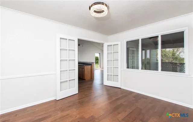 an empty room with wooden floor cabinet and windows