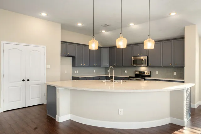 a view of a kitchen with kitchen island a sink stainless steel appliances and a wooden floor