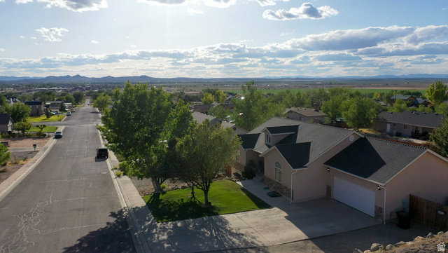 1797 Sunset Road Enoch, UT 84721 - Photo 79 of 80 Traditional stucco residence featuring a dark shingle roof, attached garage with a white panel door, and a manicured front lawn