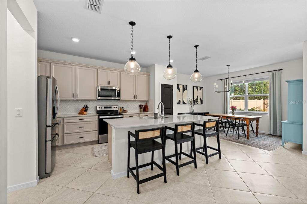 20402 Monza Loop Land O Lakes, FL 34638 - Photo 11 of 36 a kitchen with stainless steel appliances a table chairs and a refrigerator